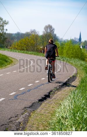 One Woman Ride Bicycle In Spring Day On Dam In Betuwe, Gelderland, Netherlands