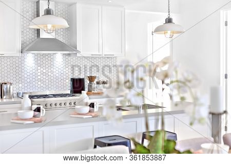 Modern Kitchen With White Decoration And Kitchenware Including Hanging Lamps, Pantry Cupboards And C