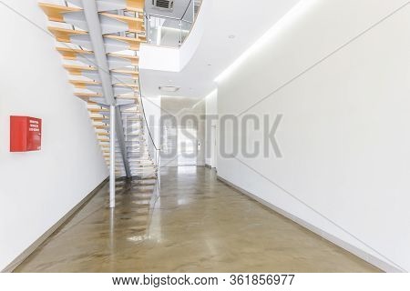 Stylish Lightwood Staircase With Glass Railings Are Supported With A Metal Poles, Eliminating The Co
