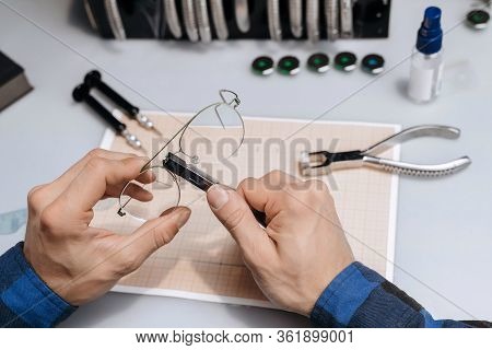 Young Professional Optical Technician Is Fixing The Bridge Of Eyeglasses In Workshop With Special Pl
