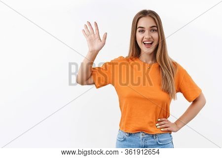 Hello Neighbour. Smiling Blond Girl Standing Near Window At Home During Self-quarantine And Waving H