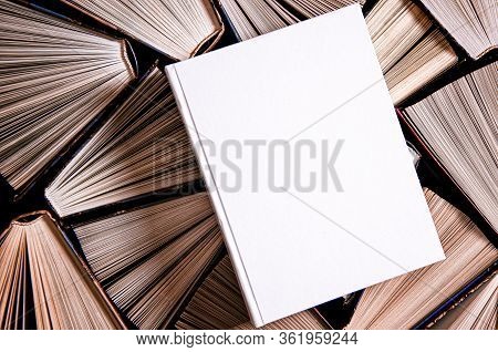 Mockup Of Closed Blank Square Book Rests On Open Old Multicolored Books