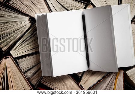 Mockup Of Closed Blank Square Book Rests On Open Old Multicolored Books