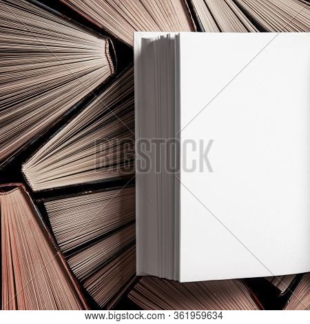 Mockup Of Closed Blank Square Book Rests On Open Old Multicolored Books
