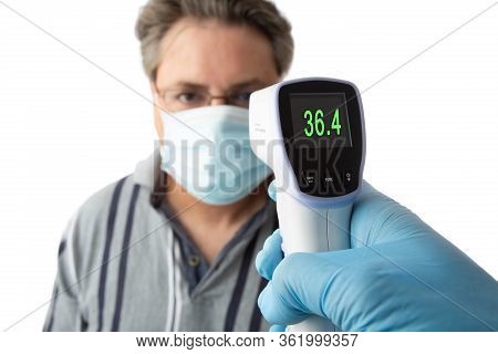 A Man Is Temperature Checked For Fever Or High Temperature Using  A Non Contact Infrared Electronic 