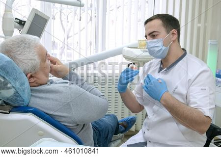 Dentist Consulting Senior Man Before Treatment In Dental Clinic. Doctor Communicates With Patient. D