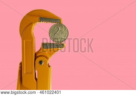 Russian Two Rubles Coin Held In An Orange Plumber Wrench On A Pink Background. Reverse Side Of The C