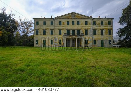 Yellow Facade Of The Villa Casino Dei Boschi Across The Green Meadow And Dramatic Sky. Boschi Di Car