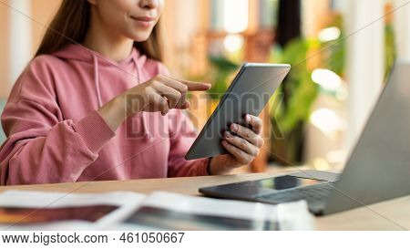 Web Based Schooling. Female Teenager Using Tablet And Laptop For Online Education, Sitting At Desk A