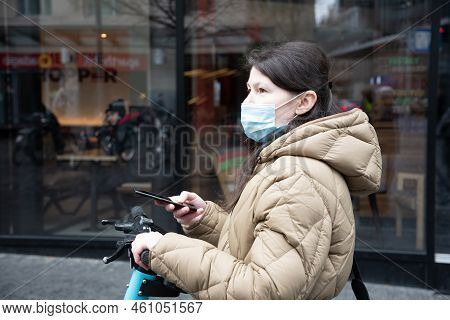 Brussels Belgium - 01.31.2022 A Young Woman In A Warm Down Jacket And A Mask