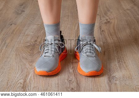 Gray Sneakers And Gray Socks On The Woman Feet. Standing Feet Shod In Mesh Sneakers With Grooved Ora