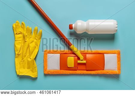 Flat Mop, Floor Cleaner And Rubber Gloves Over Blue Background. Orange Microfiber Mop With Handle, W