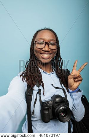 Happy Smiling Photographer With Modern Camera Device Giving Peace Sign While Taking Selfie. Photogra
