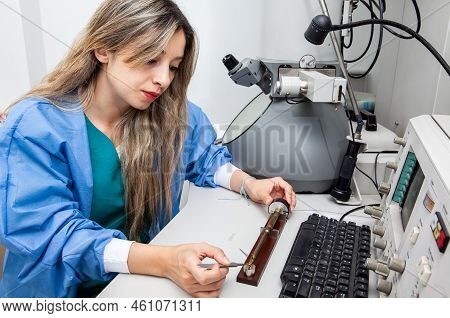 Young Female Scientist Loading A Grid With An Specimen On The Sample Holder Of A Transmission Electr