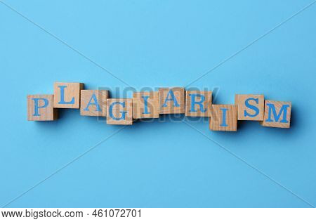 Word Plagiarism Made Of Wooden Cubes With Letters On Light Blue Background, Top View