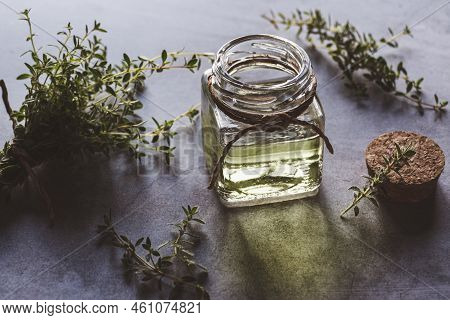 Thymus Serpyllum Infusion Oil In Bottle, Fresh Thyme Plants On Gray Table