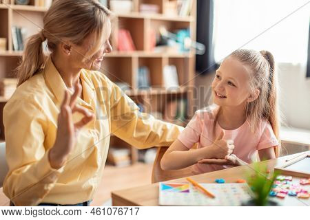 Positive Teacher Making Hand Gesture Practice Nonverbal Talk With Girl Child, Tutor Learn Sign Langu