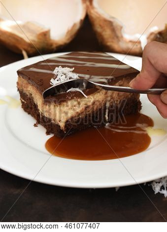 Coconut Cake On White Plate With A Spoon And Caramel Sauce