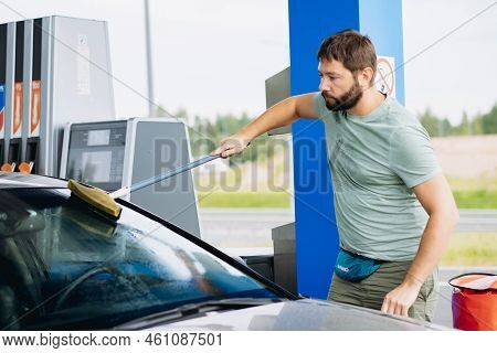 Man Washing Windshield Of Car At Gas Station. Image With Selective Focus