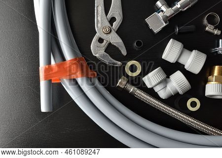 Detail Of Group Of Plumbing Materials And Tools On Black Table. Top View. Horizontal Composition.