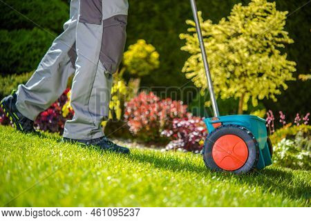 Closeup Of Spreader Gardening Equipment Being Pushed By Professional Gardener For Fertilizing The Ba