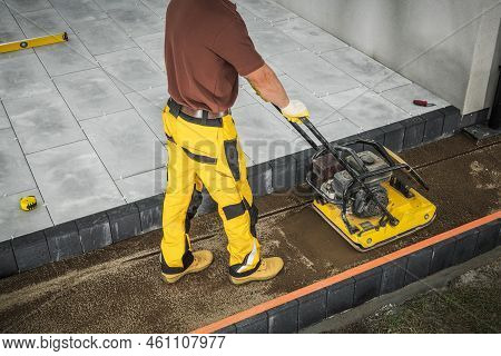 Construction Worker Building Concrete Patio. Vibrate Plate Ground Compactor Tamper In Action. Indust