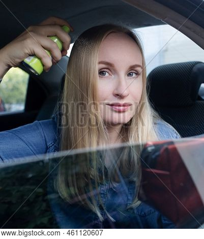Dry Shampoo. Blonde Girl Sprays Shampoo On Her Hair. The Problem Of Oily Hair While Traveling. An Em