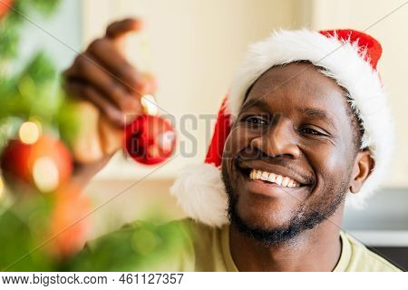 Afro American Man In Santa Hft Decorate The Christmas Tree With A Red Ball At Home