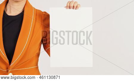 Woman Is Wearing A Radian Yellow Suit And Holding The Blank A4 Paper Board On White Background. Body
