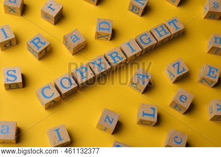 Plagiarism Concept. Word Copyright Made Of Wooden Cubes With Letters On Yellow Background