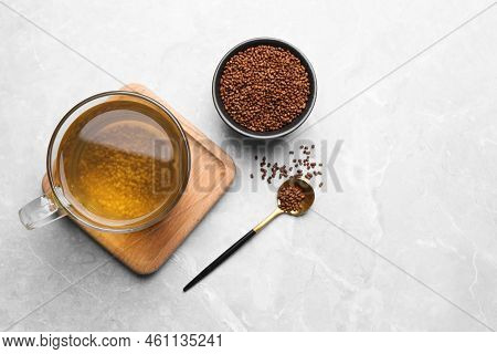 Cup Of Aromatic Buckwheat Tea And Granules On Light Marble Table, Flat Lay. Space For Text