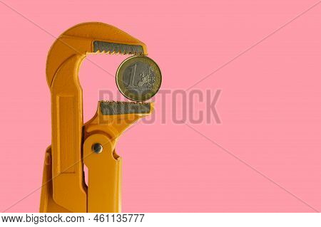 One Euro Coin Held In An Orange Plumber Wrench On A Pink Background. Reverse Side
