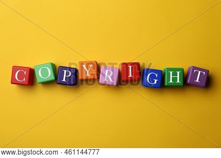 Plagiarism Concept. Word Copyright Made Of Color Cubes On Yellow Background, Top View