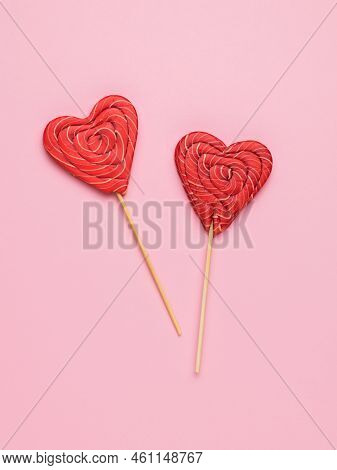 Red Candy On Sticks In The Shape Of A Heart On A Pink Background. Minimal Concept Of Sweet Life And 