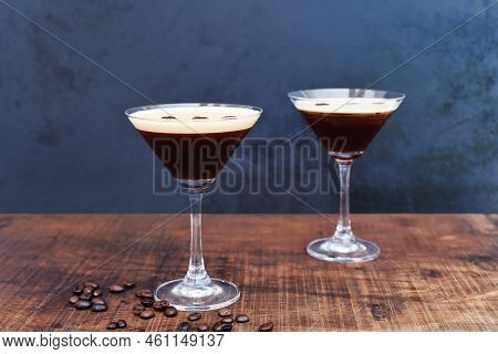 Glasses Of Espresso Martini With Coffee Beans On Wooden Table And Black Background