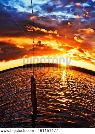 Fishing At Sunset. Catching Predatory Fish On Spinning. Sunset Colors On The Water Surface, Sunny Pa