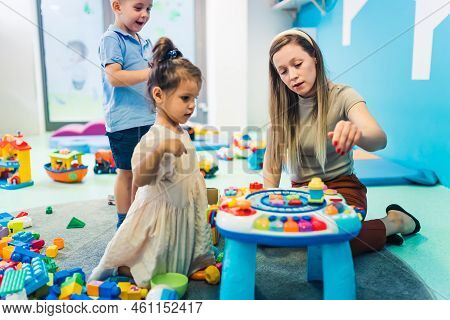 Playtime At Nursery School. Toddlers With Their Teacher Playing With Colorful Educational Sensory To