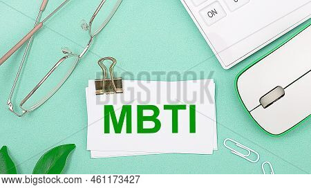 On A Light Green Background There Is A White Calculator, A Computer Mouse, Green Leaves Of A Plant, 