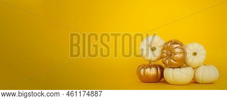 Small White And Golden Pumpkins Of The Bera Bu Variety Lie On A Yellow Background. The Concept Of Ha