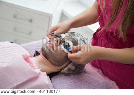 Woman Wears Protective Glasses Over Cotton Pads Over Her Eyes During The Carbon Peeling Procedure.