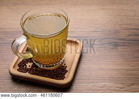 Cup Of Aromatic Buckwheat Tea And Granules On Wooden Table. Space For Text