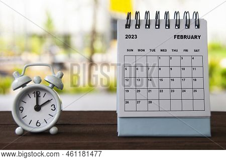 Alarm Clock Pointing At 2 O'clock With February 2023 On A Bench. Alarm Clock Pointing At 1 O'clock W