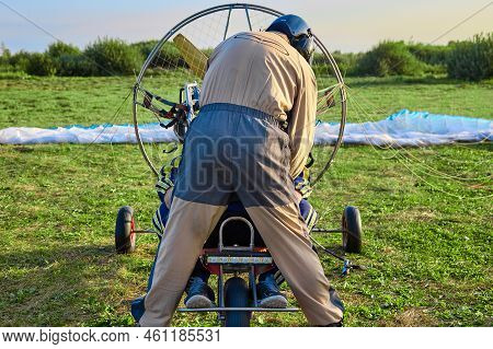 Pilot Instructor Of A Paraglider With An Engine Prepares The Equipment And The Passenger For The Fli