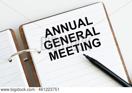 On A Light Background, A White Notebook With Are Words Agm Annual General Meeting And A Pen.