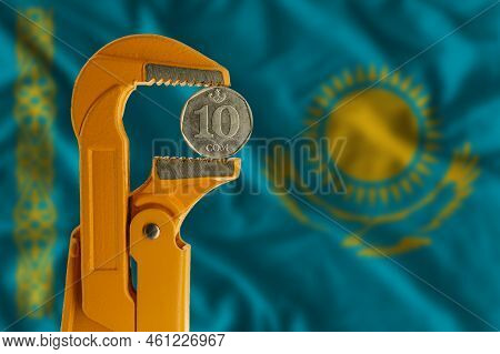 Kyrgyzstani Ten Som Coin Clamped In An Orange Plumber Wrench On The Background Of The Flag Of Kazakh