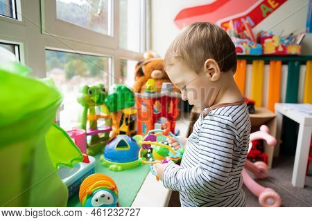 Toddler Boy Plays With Educational Toys In The Children's Room. The Study Of Colors And The Developm