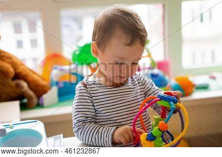 Toddler Boy Plays With Educational Toys In The Children's Room. The Study Of Colors And The Developm