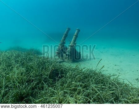 Antique Cannons On A Sandy Sea Floor. Beautiful Turquoise Water In The Background
