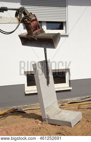 L Stones Or Angle Concrete Stones At The Construction Site Hanging On A Crane Shovel To Be Placed