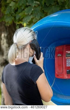 Woman Holding A Telephone Receiver Near Her Ear. Man Talking On The Phone In A Phone Booth. Woman In